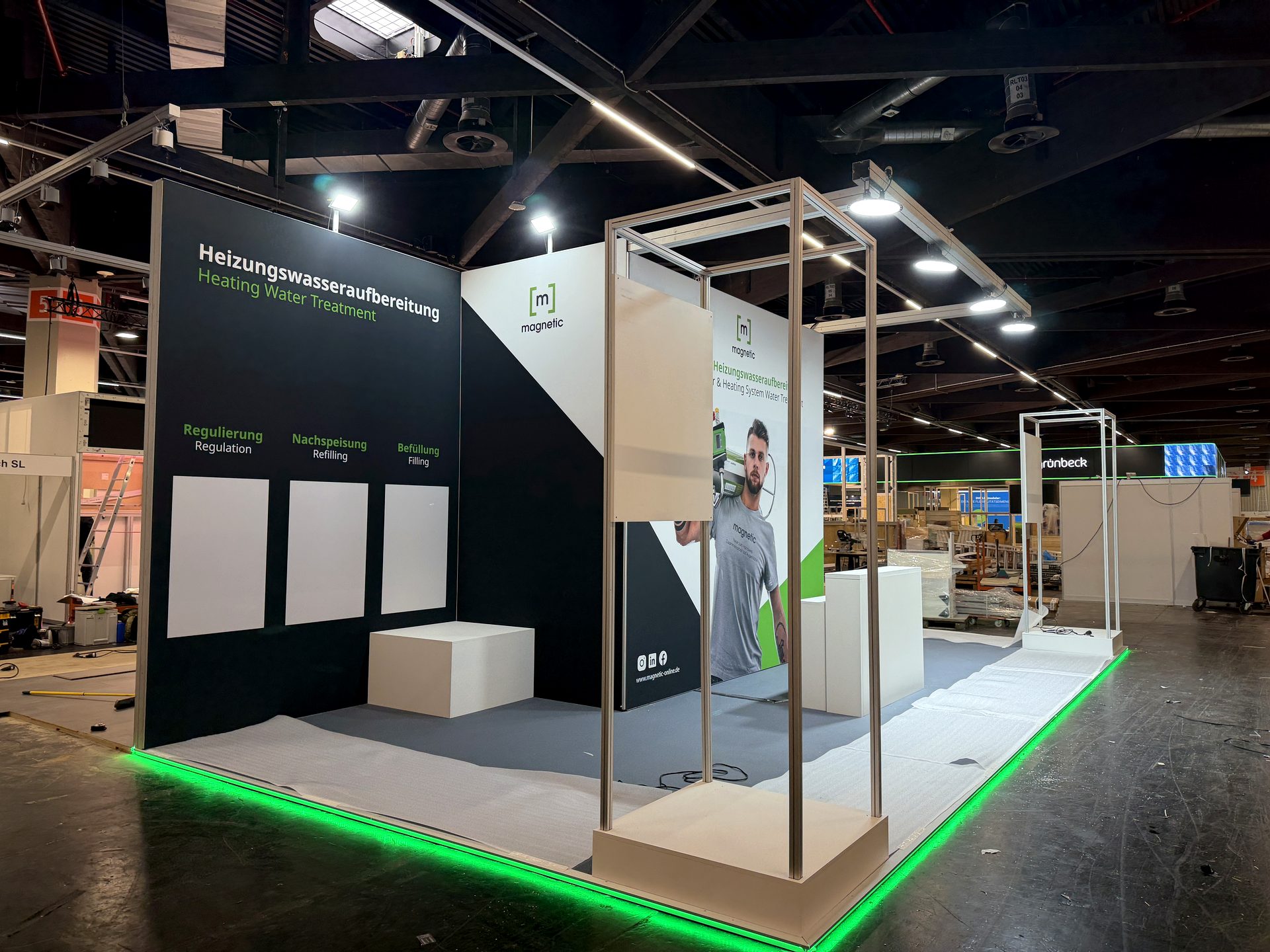 Dunkler Messestand mit beleuchtetem Rahmenbau und LED-Bodenleiste