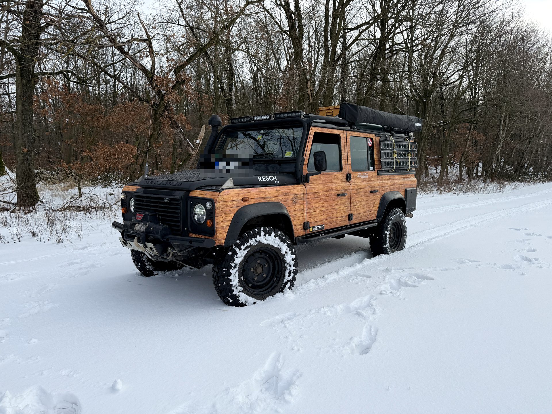 Land Rover Defender mit Holzoptik-Vollfolierung im Schnee